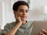 Teenager engaged in remote counseling session on a laptop from their comfortable home, emphasizing accessible mental health support.