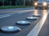 Hero image of raised pavement markers reflecting car headlights on asphalt road at night