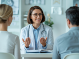 Fertility specialist consulting hopeful couple in a modern clinic with white background, symbolizing trust and care at a San Diego fertility clinic